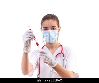 Junge Frau Doktor in weiße Uniform, maske und handschuhe mit Spritze Stockfoto