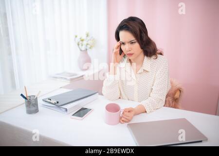 Junge Geschäftsfrau fühlt sich müde und hält den Kopf Stockfoto