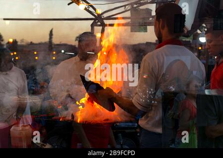 Geschäftige Abendszene marokkanischer Männer, die ein Barbecue-Dinner bei einem offenen Feuer auf dem berühmten Djemaa el Fna Platz kochen, 6. November 2017, Marrakesch, Marokko. D Stockfoto