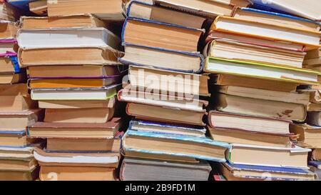 Viele gebrauchten alte Bücher in der Schulbibliothek, chaotisches Layout von Literaturstapeln, selektiver Fokus. Ein Stapel Bücher endet mit gestapeltem Hintergrund. Buch Stockfoto