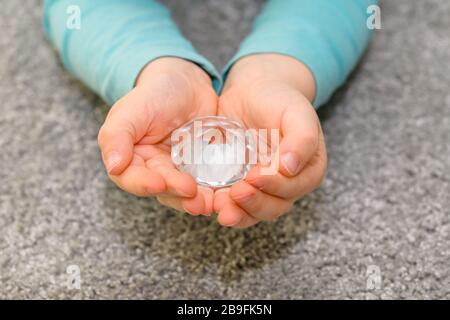 Nahaufnahme der gekuppelten Hände eines fünfjährigen Jungen, der einen großen Glaskraut hält. Der Junge hat ein türkisfarbenes Hemd. Stockfoto