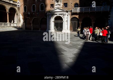 Eine Gruppe von Touristen in einem Flecken Sonnenlicht auf der Piazza dei Signori in Verona, Italien Stockfoto