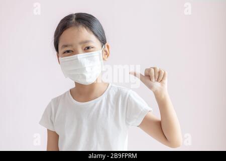 Asiatisches kleines Mädchen, das eine schützende medizinische Maske trägt. Schutz vor Grippeepidemie, Coronavirus oder COVID-19 und Smog-Krankheit. Stockfoto