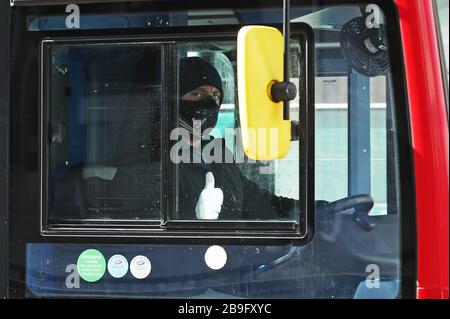 Ein Londoner Busfahrer, der eine Gesichtsmaske und Handschuhe trug, am Tag, nachdem Premierminister Boris Johnson das Vereinigte Königreich in einen Lockdown versetzt hatte, um die Ausbreitung des Coronavirus einzudämmen. Stockfoto