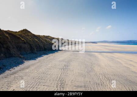 Luftbild eines leeren Gwithian-Strandes mit Wellen und Sanddünen an einem blauen Himmelstag Stockfoto