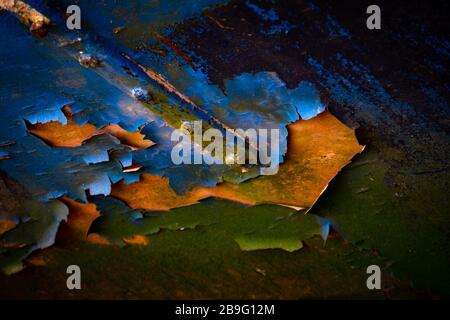 "Bunte Vernachlässigung" Nahaufnahme einer Rumpfseite mit Farbfarbe, die einfach abfällt und sich abblättert, um den darunter liegenden Rumpf mit Metalldetails zu enthüllen. Stockfoto