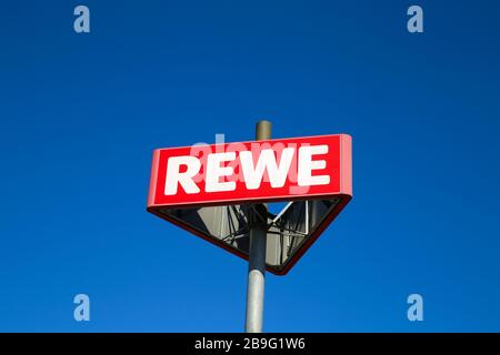 Heinsberg, Deutschland - 23. März. 2020: Nahaufnahme des isolierten Zeichens der deutschen Rewe-Supermarktkette gegen den klaren blauen Himmel Stockfoto