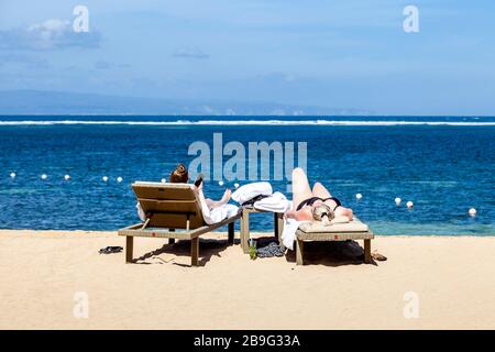 Zwei Besucher Sonnen Sich Am Strand, Sanur Beach, Sanur, Bali, Indonesien. Stockfoto