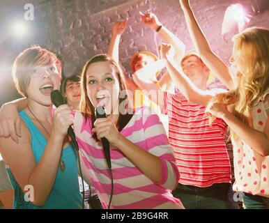 Fröhliche Teenager-Freunde singen Karaoke auf der Party Stockfoto