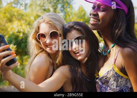 Fröhliche Teenager-Freundinnen, die selfie mit Smartphone auf einer sonnigen Terrasse einnehmen Stockfoto