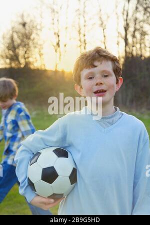Portraitjunge mit Freckles, die Fußballball im Park halten Stockfoto