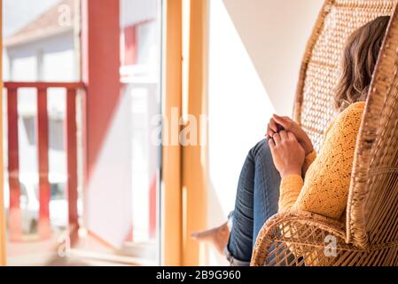 Optimistische Frau, die zu Hause in einem konfortistischen Rattanstuhl sitzt Stockfoto