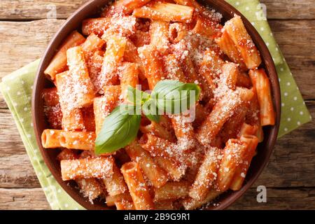 Servieren von Tortiglioni-Pasta mit Parmesanbasil in Tomatensauce in einem Teller auf dem Tisch. Horizontale Draufsicht von oben Stockfoto