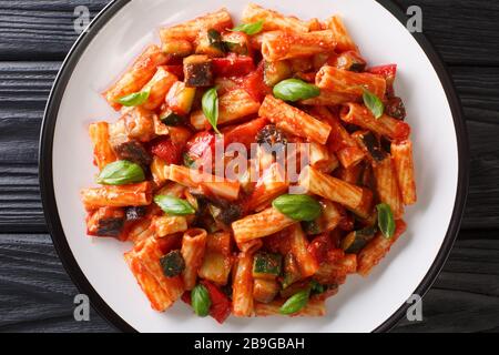 Talian Pasta Tortiglioni mit Auberginen, Zucchini, Pfeffer und Basilikum in Tomatensauce in einer Platte auf dem Tisch. Horizontale Draufsicht von oben Stockfoto