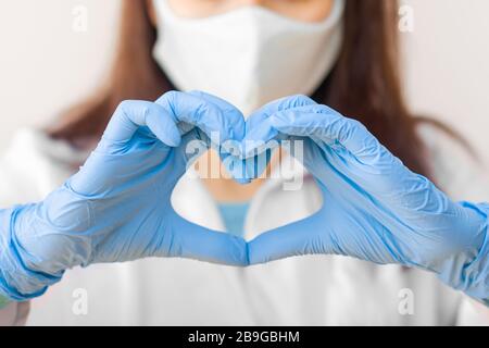 Stoppen Sie SARS-COV, SARSCoV, Virus 2020, MERS-COV, chinese Virus COVID-19. Closeup Frauen Hand in blauen medizinischen Handschuhen zeigen Herzschild. Konzept von Stockfoto