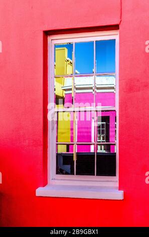 Fensterreflexion umgeben von rot bemalten Wänden farbenfroh dekorierter Häuser im muslimischen Viertel Bo Kaap in Kapstadt Südafrika Stockfoto