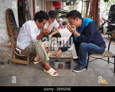 Männer, die auf den Straßen von Hanoi Schach (Checkers) im vietnamesischen Stil spielen Stockfoto