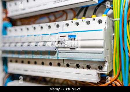 Einphasige Sicherungen in Stellung OFF und Reststromschutz in STELLUNG ON. Viele graue Schalter in einer Reihe, Hauptsicherungskasten. Stockfoto