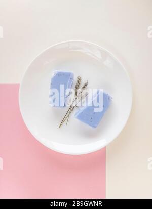 Hausgemachte Lavendel-Seifenbar und trockene Lavendelblüten auf minimalistischem Hintergrund. Satz von plastikfreien und abfallfreien Körperpflegeartikeln. Stockfoto