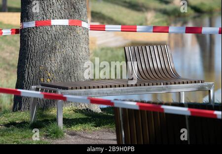 Luckenwalde, Deutschland. März 2020. Die Bänke im Nuthepark sind mit rotem und weißem Wegeband abgedrandet. Mit der Kennzeichnung will die Stadt das Verbot von Menschenmassen in Parks und öffentlichen Bereichen durchsetzen, das aufgrund der Corona-Pandemie erlassen wurde. Credit: Soeren Stache / dpa-Zentralbild / dpa / Alamy Live News Stockfoto