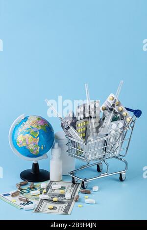 Verschiedene Kapseln, Tabletts und Medikamente im Einkaufswagen und Pillen, die aus der weißen Flasche auf blauem Hintergrund mit geografischem Globus verschüttet werden. Kaufen und kaufen Stockfoto