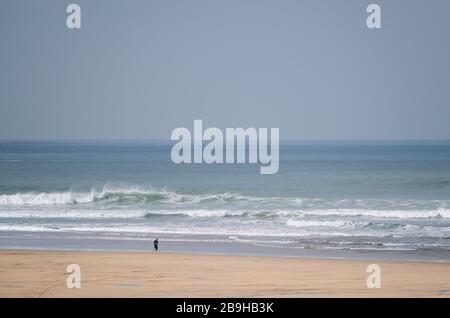 Newquay, Cornwall, Großbritannien. März 2020. Ein Einheimischer, der die Regierung berät und sicherstellt, dass er sich selbst isoliert, wenn er an einem völlig leeren Fistral Beach in Newquay in Cornwall entlang der Küstenlinie verläuft. Gordon Scammell/Alamy Live News. Stockfoto