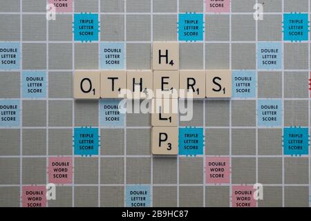 London, Großbritannien. März 2020. Scrabble Board mit Formulierungen und Wörtern im Zusammenhang mit Coronavirus Hilfe, Positivität und Unterstützung. HELFEN SIE ANDEREN Stockfoto