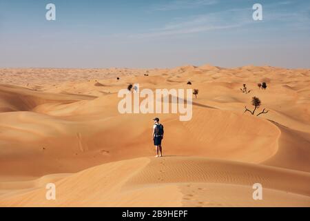 Junger Mann, der mitten in der Wüste auf Sanddüne steht. Abu Dhabi, Vereinigte Arabische Emirate Stockfoto