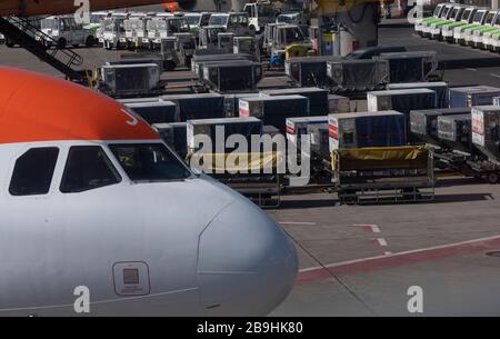 Berlin, Deutschland. März 2020. Zahlreiche leere Gepäckwagen stehen neben einem Flugzeug am Flughafen Tegel. Credit: Paul Zinken / dpa / Alamy Live News Stockfoto