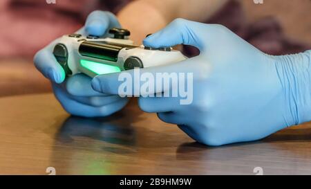 Junge männliche Hände in medizinischen Einzelhandschuhen, die in Quarantänezeit die Gegenspielstation über den Tisch legen. Sicheres, soziales Distanzierungskonzept Stockfoto