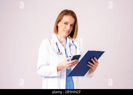 Porträtaufnahme von Textnachrichten von Frauen mittleren Alters, während sie auf isoliertem Hintergrund stehen. Stockfoto