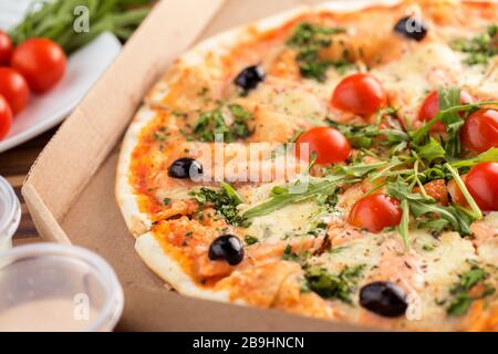 Italienische Pizza mit dünner Kruste und Lachs im Karton Stockfoto
