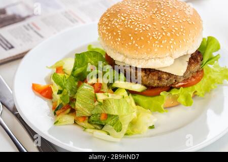 Köstlicher gegrillter Rinderburger auf einem Teller mit Salatgarnierung Stockfoto