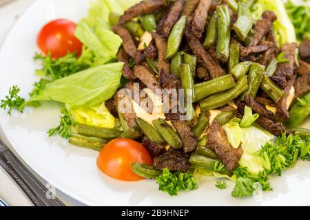 Leckerer Salat mit geröstetem Spargel und Rindfleisch auf weißem Teller Stockfoto