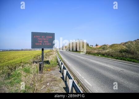 Ein Schild auf der A367 in Bath empfiehlt Autofahrern, zu Hause zu bleiben, um die NHS zu schützen und am Tag nach der Versperrung durch Premierminister Boris Johnson Leben zu retten, um die Ausbreitung des Coronavirus einzudämmen. Stockfoto