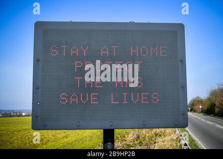 Ein Schild auf der A367 in Bath empfiehlt Autofahrern, zu Hause zu bleiben, um die NHS zu schützen und am Tag nach der Versperrung durch Premierminister Boris Johnson Leben zu retten, um die Ausbreitung des Coronavirus einzudämmen. Stockfoto