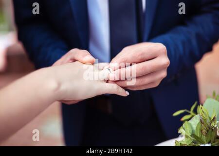 Bräutigam mit goldenem Trauring auf den Finger der Frau Stockfoto