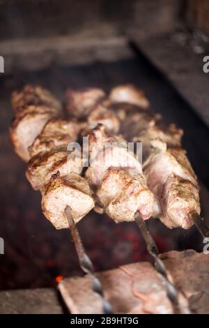 Schweinefleisch auf Spießen gegrillt. Kochende Schaschlik. Grill auf Holzkohle gegrillt. Geringe Schärfentiefe Stockfoto