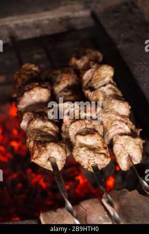 Braten von Schweinefleisch auf Spießen. Grillplatz auf Holzkohle. Kochende Schaschlik Stockfoto