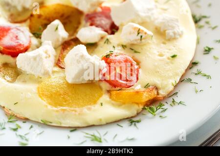 Köstliches Omelett mit Tomaten, Kartoffel und Ziege oder griechischem Fetakäse Stockfoto