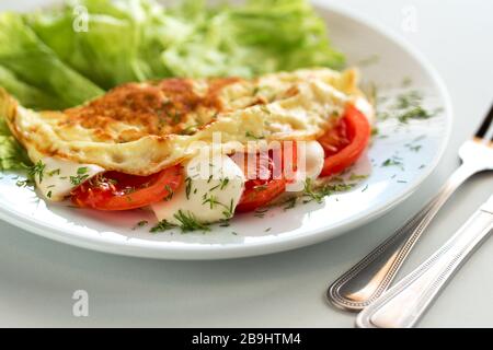 Köstliches Omelett mit Tomaten, Salat und Mozzarella-Käse Stockfoto