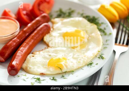 Köstliche Würstchen mit Spiegeleiern und Tomaten zum Frühstück Stockfoto