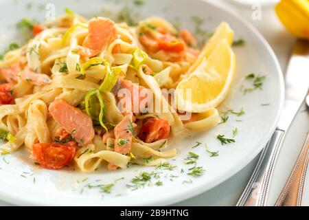 Köstliche Tagliatelle Pasta mit Lachs, Tomaten, Zwiebel und Zitrone. Italienische Meeresfrüchte Spaghetti mit Lachs und Sauce Stockfoto