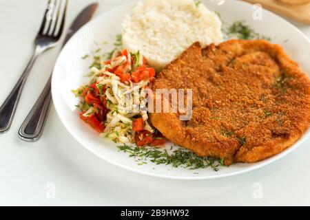 Deutsches Schweineschnitzel mit Reis und Kohlsalat Stockfoto