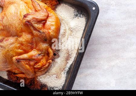 Hühnchen gebacken im Ofen auf einer dicken Salzschicht auf einer Metallschale die Ansicht von oben. Stockfoto