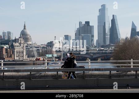 London, Großbritannien. März 2020. Zwei Personen, die am ersten Tag von Lockdown in London an der Waterloo Bridge mit Gesichtsschutzmasken spazieren, überblicken die City of London und die St Paul's Cathedral. (Foto von Sam Mellish / Alamy Live News) Stockfoto