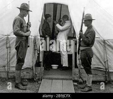 Amerikanischer Soldat bekommt Kehle versprüht, um Influenza zu verhindern. Dez. 1918. Medizinisches Zelt im Love Field, Dallas, Texas, während der "spanischen" Grippe-Pandemie 1918-19. 1918-1919. Eine Epidemie der "Panischen Grippe" breitete sich weltweit aus. Mindestens 20 Millionen starben, obwohl einige Schätzungen die endgültige Maut auf 50 Millionen beziffert haben. Stockfoto