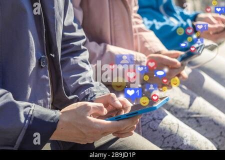 Nutzer verwenden ein soziales Netzwerk mit Benachrichtigungssymbolen auf Smartphones. Die Hände von Teenagern, die Live-Streaming-Videos auf ihrem Handy ansehen. Stockfoto