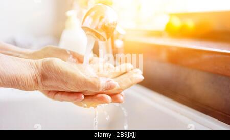 Ältere Frauen waschen die Hände mit flüssiger Seife unter Wasser am Hahn Stockfoto