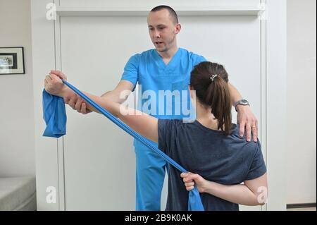 Ein junger männlicher Physiotherapeut hilft einem Teenager-Mädchen bei Dehnübungen Stockfoto